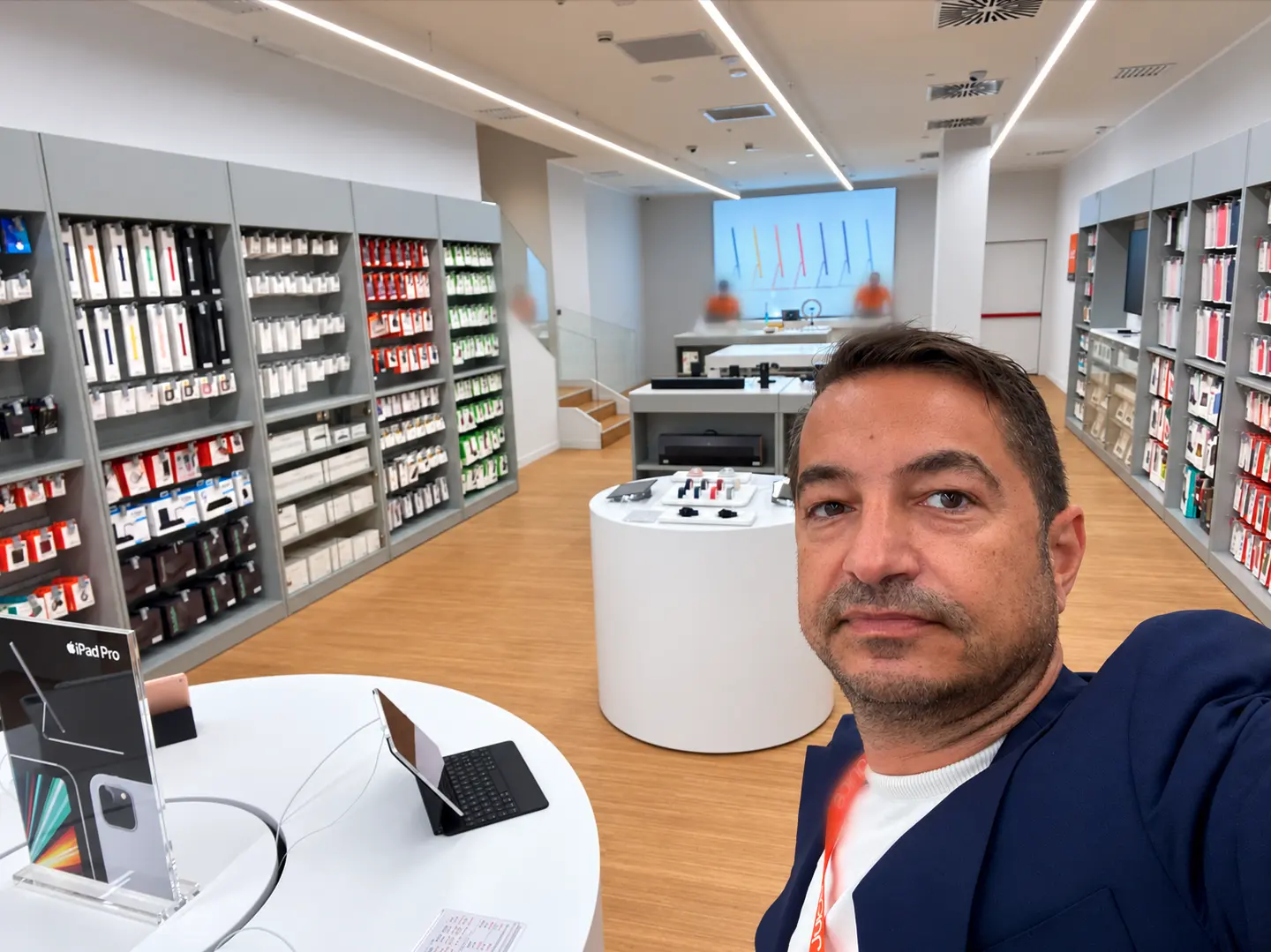 Daniele Perin in un negozio di elettronica, tra le pareti di accessori e i banchi espositivi